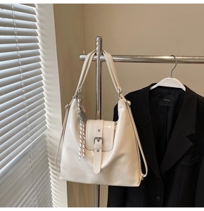 Gros plan du sac cabas en cuir PU blanc cassé avec boucle en métal et pompon à rayures