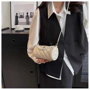Detail of a white quilted cylinder bag with pearl strap and star charm on a model