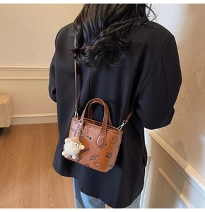 Detailed close-up of brown embossed bucket bag with cute sheep charm and cartoon patterns