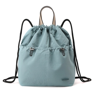 Detail of blue nylon drawstring backpack with top handle and brand logo patch