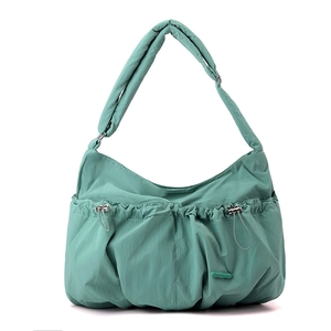 Close-up of mint green pleated nylon bag featuring drawstring details and branded logo