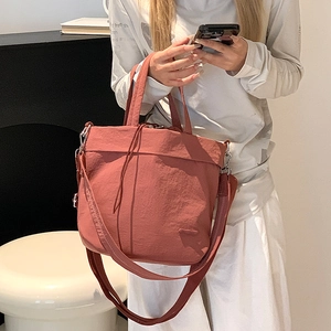 Detail of the warm brick red nylon drawstring crossbody bag with durable top handles