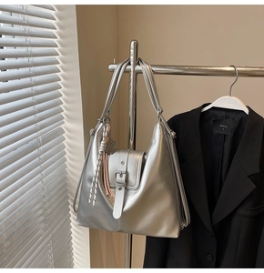 Détail du sac hobo argenté métallisé avec sangles à boucle et breloques à nœuds sur cintre