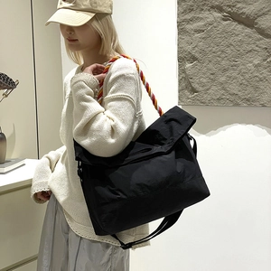 Détail du sac cabas en toile noir avec bandoulière en corde tressée rouge et jaune