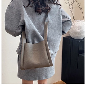 Detail of grey lychee leather bucket bag with UZBAG logo and soft pebble texture