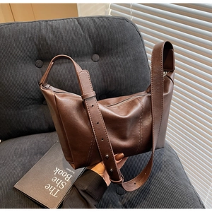 Detailed view of adjustable shoulder strap and metal rivets on coffee faux leather hobo bag