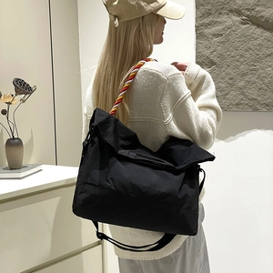 Détail d'un sac cabas en toile noire avec poignées en corde tressée tricolore