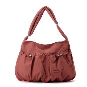 Detail view of the rust red nylon bag with pleated texture and adjustable shoulder strap