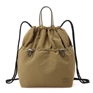 Detail of olive green nylon drawstring backpack featuring a branded logo and pocket