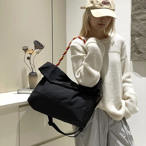 Détail du grand sac de voyage en toile noire avec une sangle décorative tressée tricolore