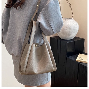 Close-up of grey pebbled leather bucket bag featuring UZBAG embossed logo and handles