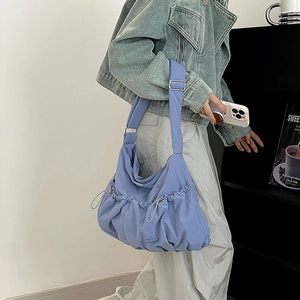 Detail of light blue nylon bag featuring side drawstring ruching and wide adjustable strap
