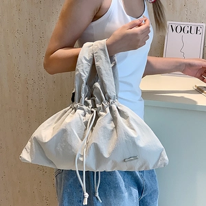 Close-up of light gray nylon drawstring handbag with soft pleated texture and wide strap