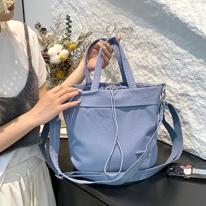 Detail of light blue nylon drawstring tote bag with adjustable shoulder strap and texture