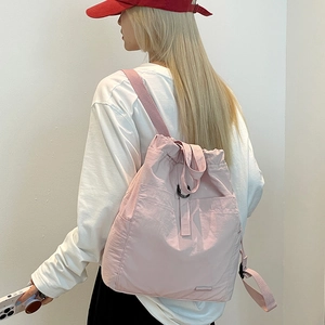 Detailansicht eines leichten blassrosa Nylon-Rucksacks mit Kordelzug an einem Model