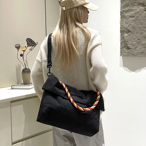 Vue détaillée du sac bandoulière en toile noire avec corde tressée rouge et jaune décorative