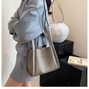 Detailed view of gray lychee leather bucket bag with top handle and brand logo