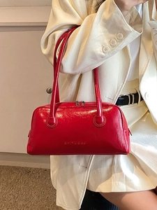 Glossy red patent leather Boston bag with double handles shown on shoulder with light blazer
