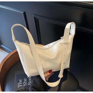Detailed close-up of cream white crossbody bag on vintage chair with adjustable strap