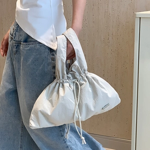 Detail of cream-colored nylon handbag featuring drawstring cloud design and soft texture