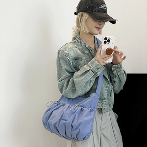 Side view of lavender pleated nylon crossbody bag worn by a model in casual denim jacket