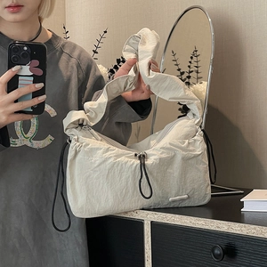 Detail of cream pleated nylon shoulder bag showing ruched texture and fashion brand label