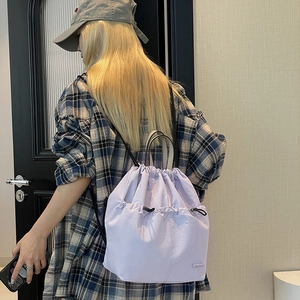 Lavender drawstring backpack detail showing light nylon fabric and twin front pockets