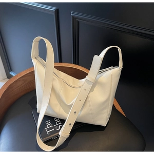 Detail of adjustable strap with silver cylindrical buckle on beige faux leather bag