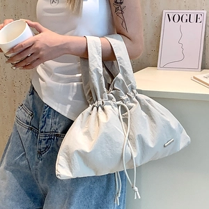 Detail of water-resistant white nylon handbag with drawstring closure and metal logo