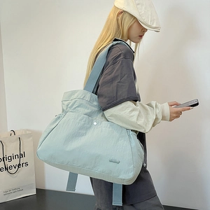 Detailansicht der mintblauen Nylon-Tasche mit Textur und vorderer Druckknopftasche