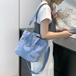 Detail of light blue nylon drawstring bag with adjustable strap on a casual model outfit
