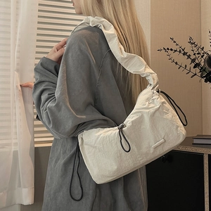 Detail view of white ruched nylon cloud bag with black drawstring in a home setting
