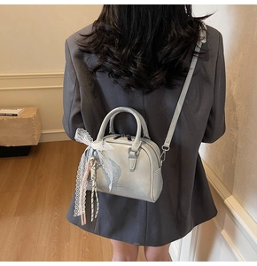 Close-up of mini Boston bag with delicate white lace bow and elegant fringe pendant
