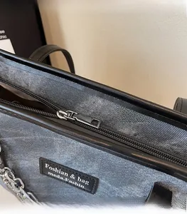 Détail de la fermeture argentée et du cabas en denim gris avec garniture en cuir noir