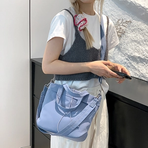Close-up of light blue nylon bag detail with silver metal buckle and adjustable shoulder strap