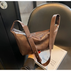Detail of dark brown crescent shoulder bag with glossy vintage PU leather texture