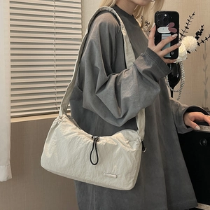 Detail of beige nylon cloud bag showing drawstring closure and ruched texture fabric