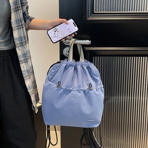 Detailed close-up of light blue nylon drawstring backpack hanging on a black door handle