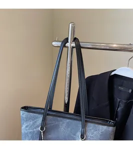 Détail d'un grand sac cabas texturé avec longues anses en cuir noir et étiquette de marque