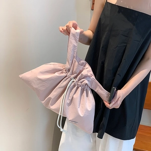 Detail of light pink waterproof nylon tote bag with drawstring closure and wide handle