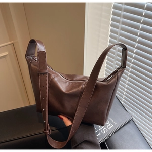 Detail view of adjustable strap holes on a dark brown matte leather hobo shoulder bag