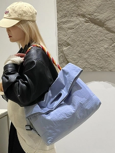 Grand sac cabas bleu clair en toile avec bandoulière tressée tricolore porté par un mannequin