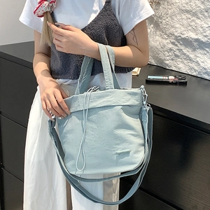 Close-up of light blue nylon drawstring bag showing texture and shoulder strap detail
