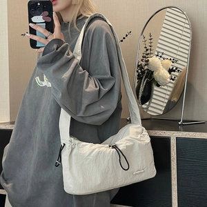 Minimalist beige nylon hobo bag with drawstring detail shown in a mirror selfie