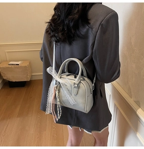 Detail of light grey bowling bag with white lace bow on shoulder of female model