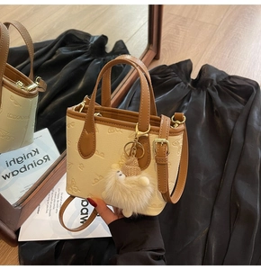 Detail of beige contrast handbag with butterfly embossing and plush sheep charm