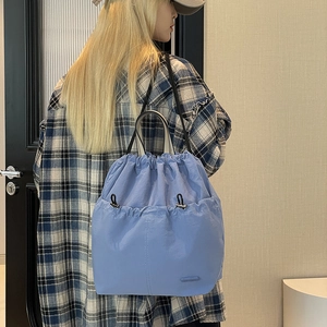 Detail of light blue drawstring backpack with tiered front pocket and adjustable cord lock