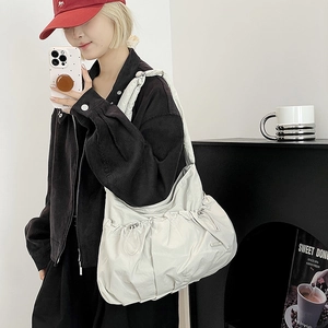 Close-up of cream pleated nylon crossbody bag with adjustable drawstring side detail