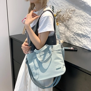 Close-up of light blue nylon shoulder bag with adjustable strap and brand patch detail