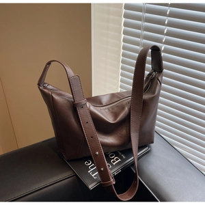 Detail of dark brown dumpling bag with matte leather texture and silver metal studs